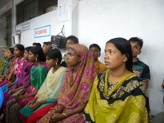 Seated rows of Bangladeshi women and men look forward attentively