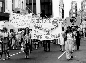 Women march through the city of Sydney behind large pro-choice banners