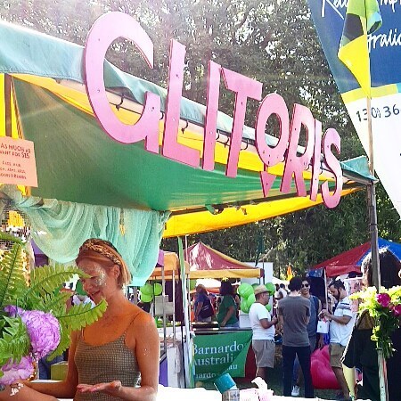 A woman with glitter on her face stands in a stall, with the title: Glitoris