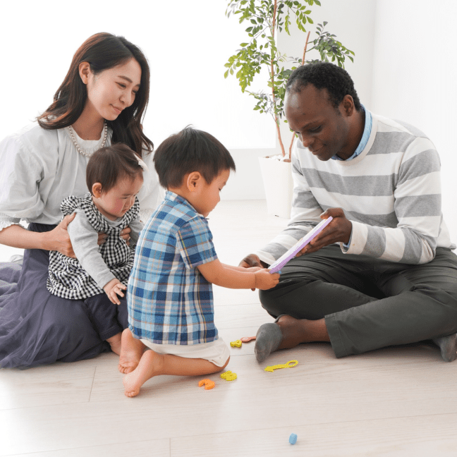 An Asian woman and Black man play with two Asian babies