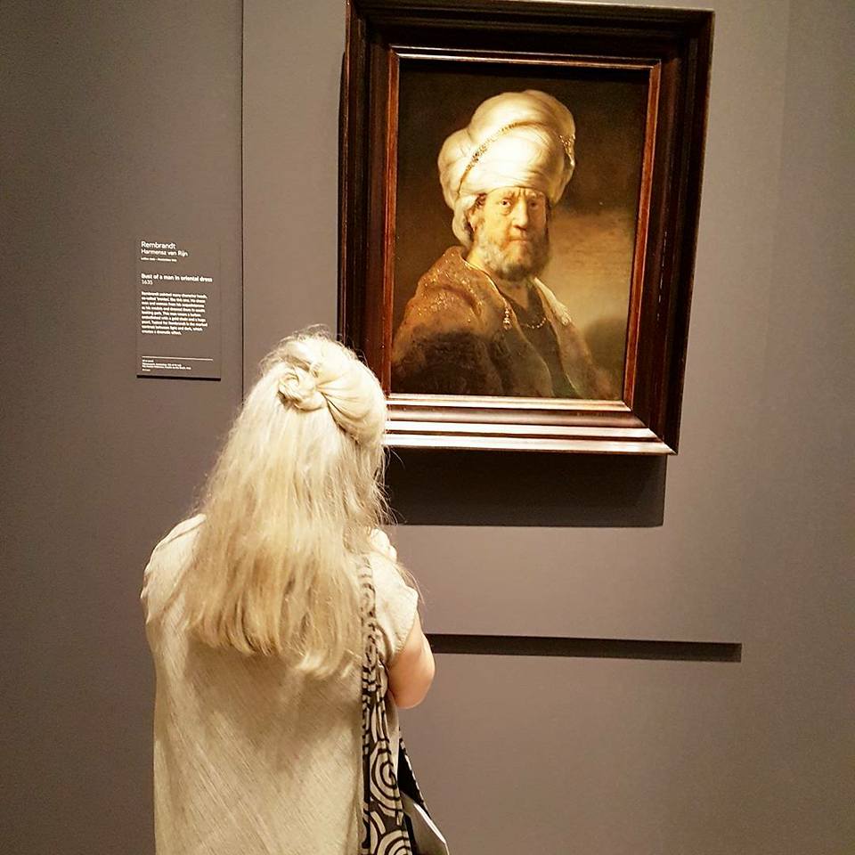 Woman with long white hair stares at “Bust of a Man in Oriental Dress