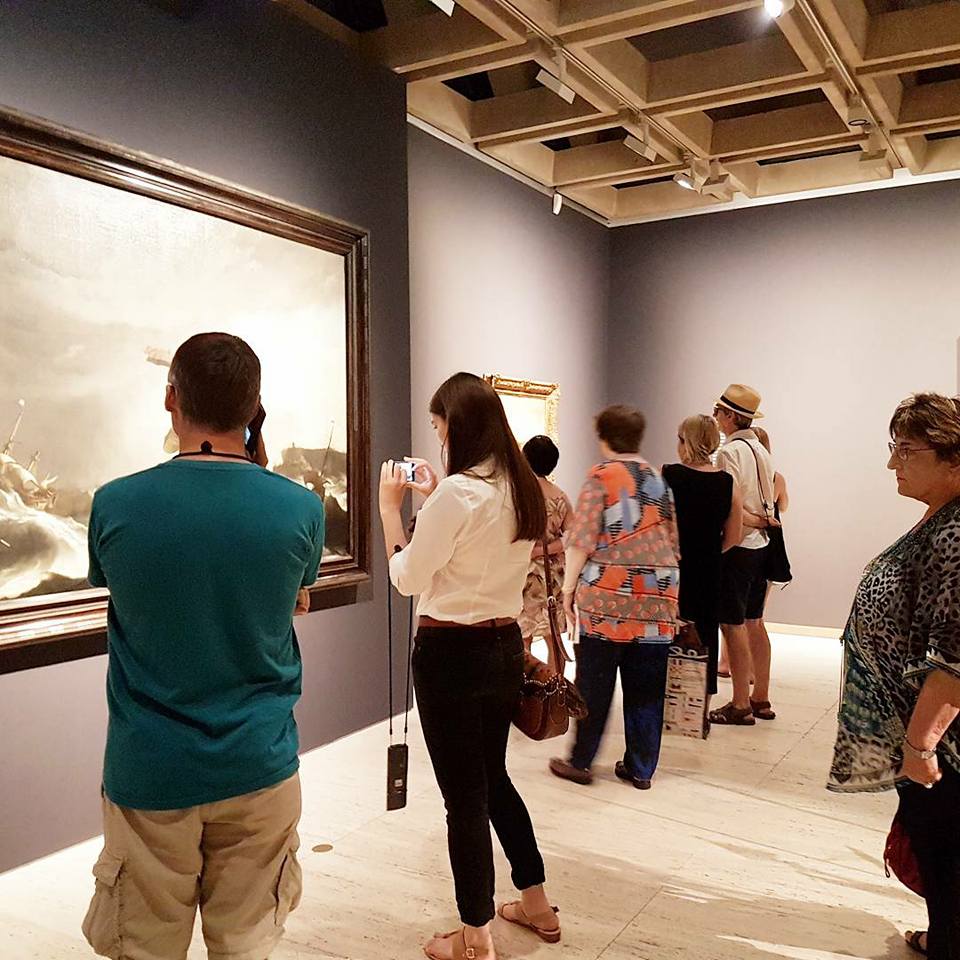 People take photos of the large paintings on display