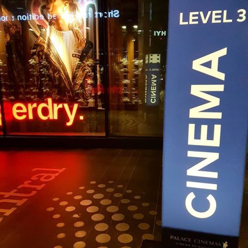 Sign saying Cinema Level three, with shops in the background