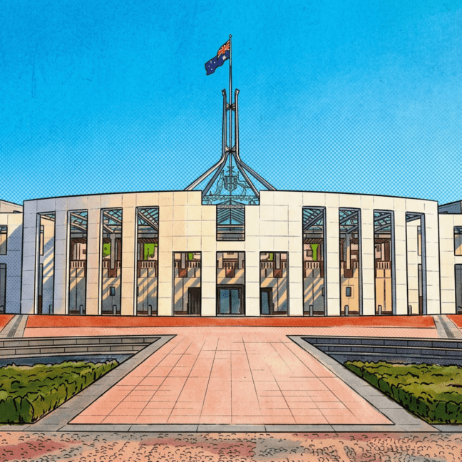 The front of Parliament House, showing a white building, with a colonnade façade and a four-legged steel flagpole, where the Australian flag flies. There is a paved areas and grass on either side