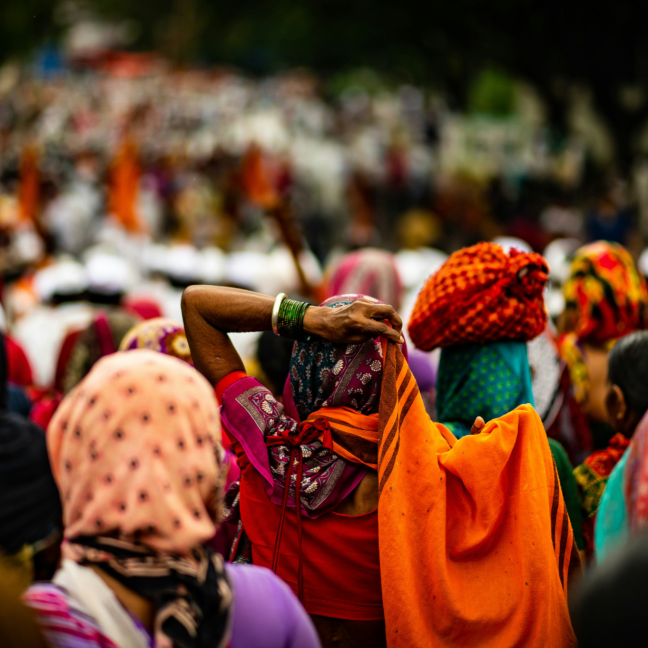 Crowd of Indian women seen from behind wearing colourful saris outdoors